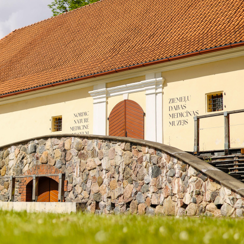 Pilsmuižas klēts celta 18. gadsimtā, Ķieģelsarkans jums, bē&scaron;a ēkas fasāde ar baltām, dekoratīvām kollonām, kas rotā lielās arkveida muzeja ieejas durvis.