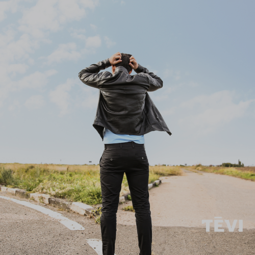 Vīrietis stāv ceļa vidū ar muguru pret kameru, rokas uzliktas uz galvas, skatoties tālumā pie ceļa sazarojuma zem gai&scaron;ām debesīm. Attēls simbolizē neziņu, izvēli un nepiecie&scaron;amību pēc atbalsta izglītības ceļā.