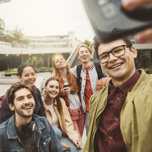 Septiņi smaido&scaron;i jaunie&scaron;i kopā fotogrāfē selfiju.