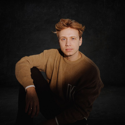 Attēlā redzams Radio TEV raidījumu vadītājs Lauris Zalāns, kur&scaron; vadīs konkrēto diskusiju. Attēlā Lauris ir uz tum&scaron;a fona, tādējādi mākslinieciski norādot uz emocionāli negatīvu stāvokli.