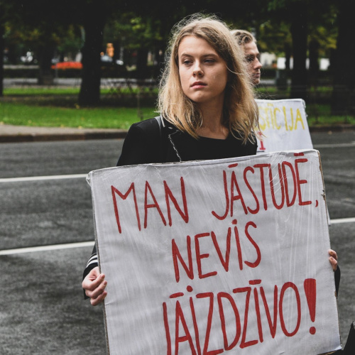 Foto no protesta akcijas "Klusuma brīdis augstākajai izglītībai", ko organizēja Latvijas Studentu apvienība. Attēlā attēlota meitene, kas tur rokās plakātu ar vēstījumu "MAN JĀSTUDĒ, NEVIS JĀIZDZĪVO". Protests norisinās lietainā laikā uz ielas pretim Ministru kabinetam Rīgā.

Foto autore: Izabella Rumkovska