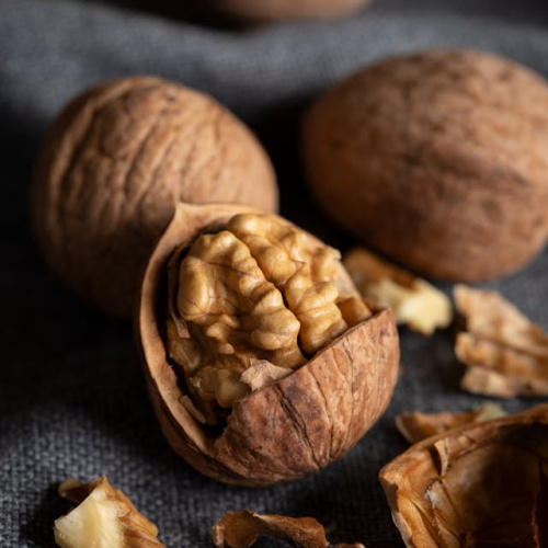 Trīs veseli un viens pār&scaron;ķelts valrieksts uz pelēka, tum&scaron;a auduma fona