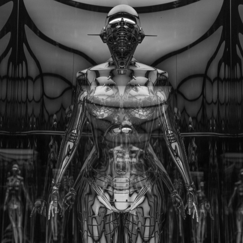 Melbalts foto, tās priek&scaron;plānā redzams cilvēks-robots, kā mākslīgā intelekta iemiesojums, tā fonā, tālumā daudzi lidzīgi radījumi.