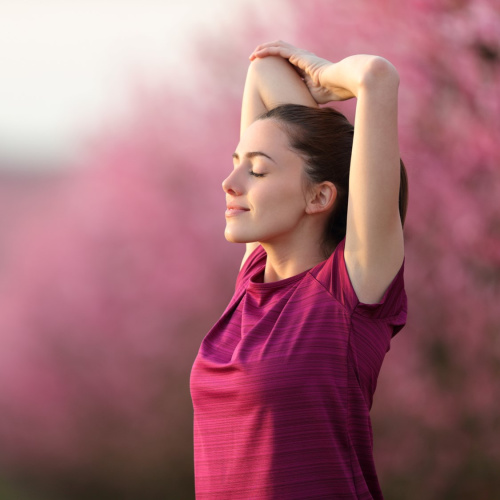 Meitene sarkanā sporta kreklā izstiepj rokas, saliektas elkoņos.