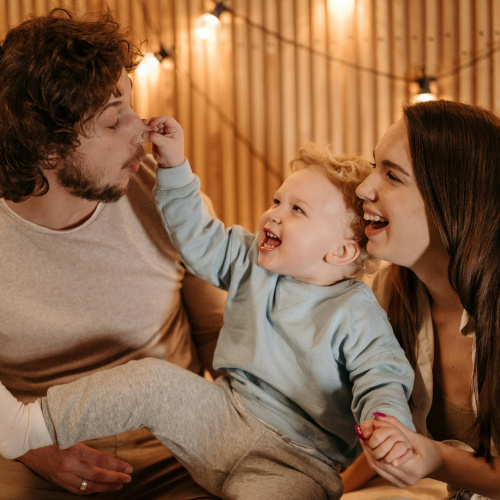Mamma, tētis un bērns smejas un jokojas.